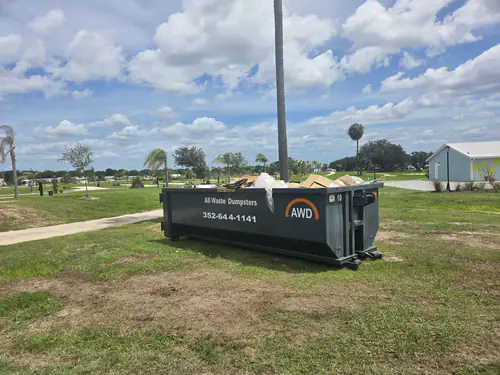All Waste Dumpsters container number 10 on mowed grass beside a walkway at a newly landscaped commercial property in Ocala