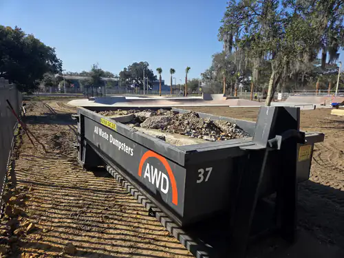 All Waste Dumpsters container number 37 loaded with broken concrete on graded sand inside the construction fence at a Marion County skate park renovation